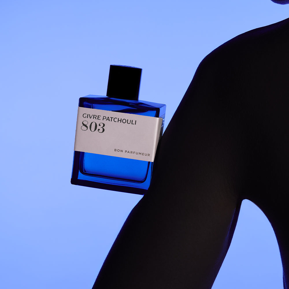 Bon Parfumeur 803 Givre Patchouli Parfumflakon am Körper eines Models vor blauem Hintergrund