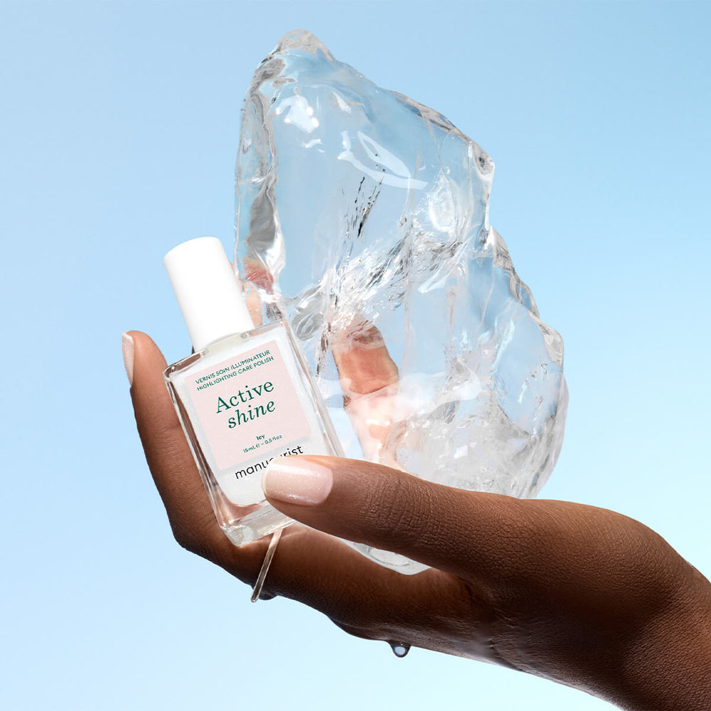 Manucurist Active Shine Icy Nagellack in einer Hand vor einem großen Eisblock